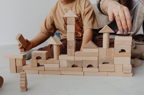 Free Photo of a Kid and Another Person Placing Wooden Blocks Stock Photo
