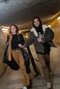 Woman in Black and White Hoodie Standing Beside Woman in Black and Brown Coat
