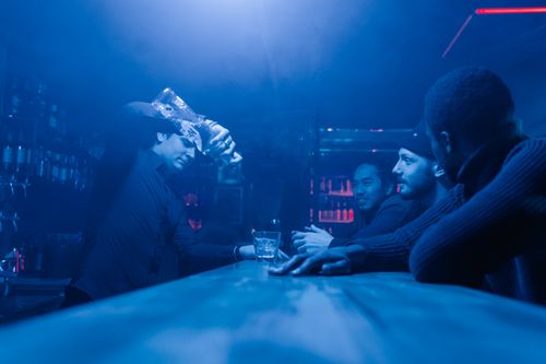 Free A bartender pours drinks for friends enjoying a night out at a club. Stock Photo