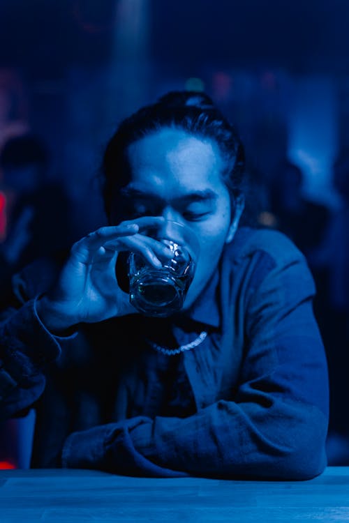 Photograph of a Man in a Bar Drinking from a Glass