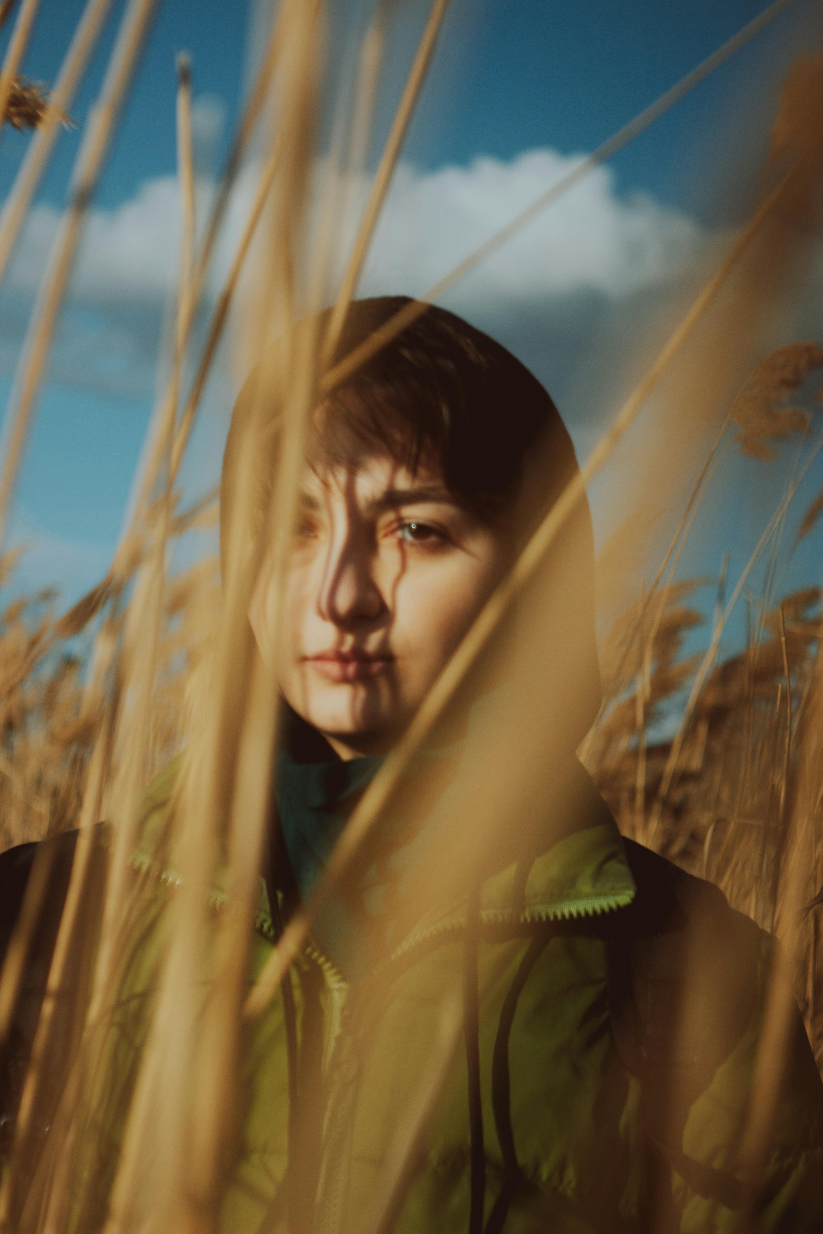 woman in green jacket standing on wheat field