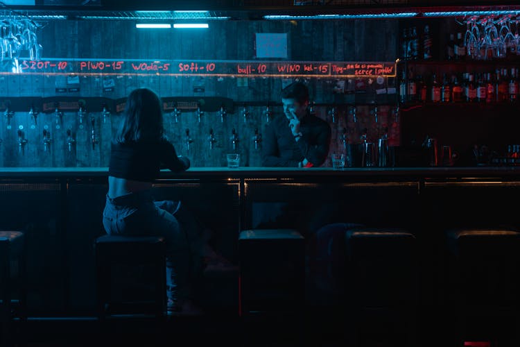 Photo Of A Woman Sitting Near The Bartender