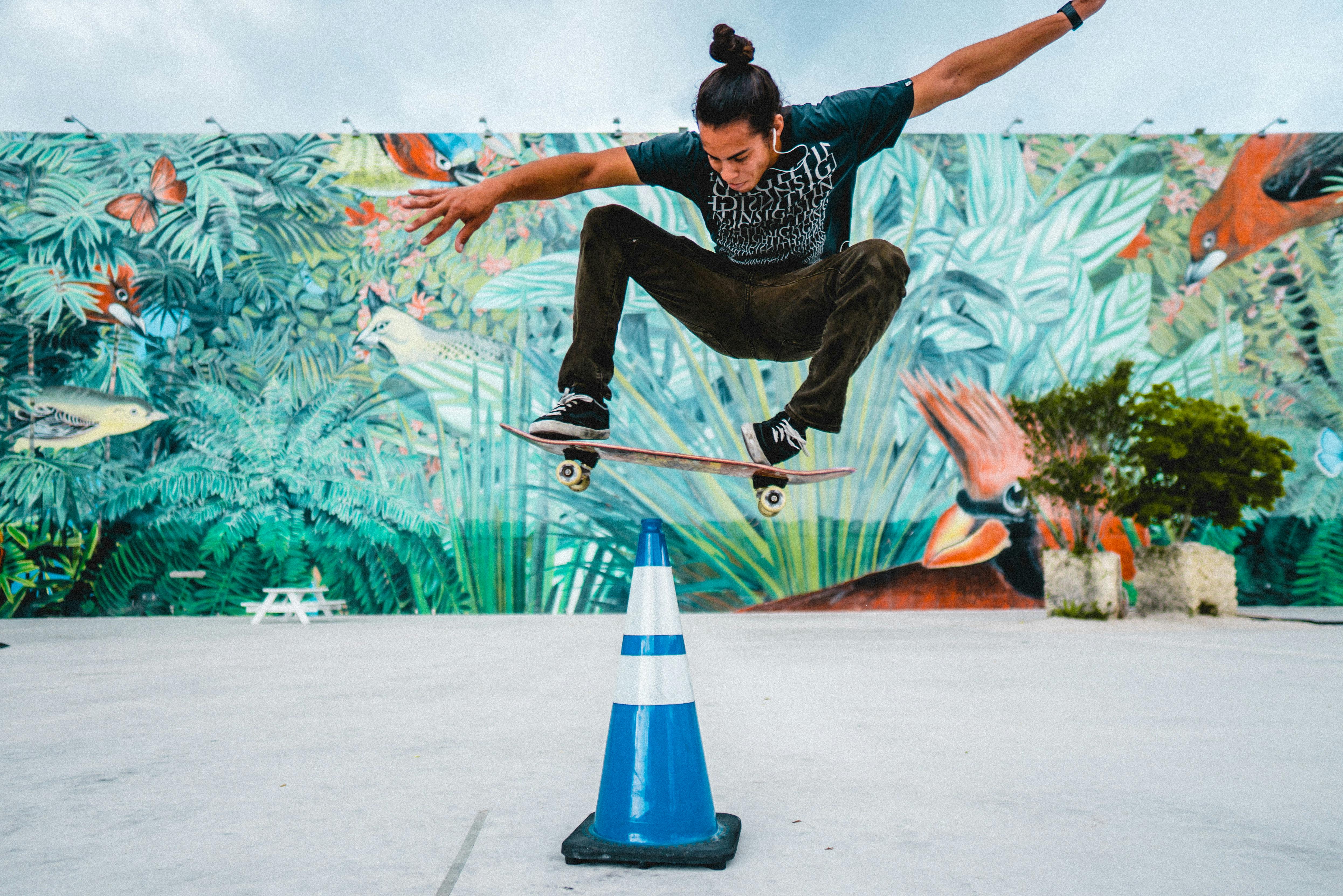 Dynamic skateboarding trick in front of a colorful mural showcasing urban art.