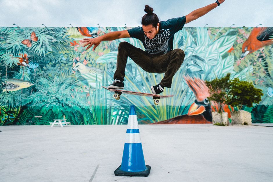 Dynamic skateboarding trick in front of a colorful mural showcasing urban art.