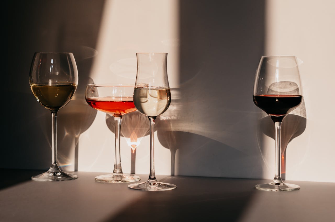 Calici assortiti con diversi vini disposti su un tavolo illuminato dal sole