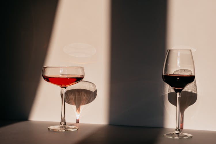 Glasses Of Red Wine And Cocktail Served On Table In Daylight