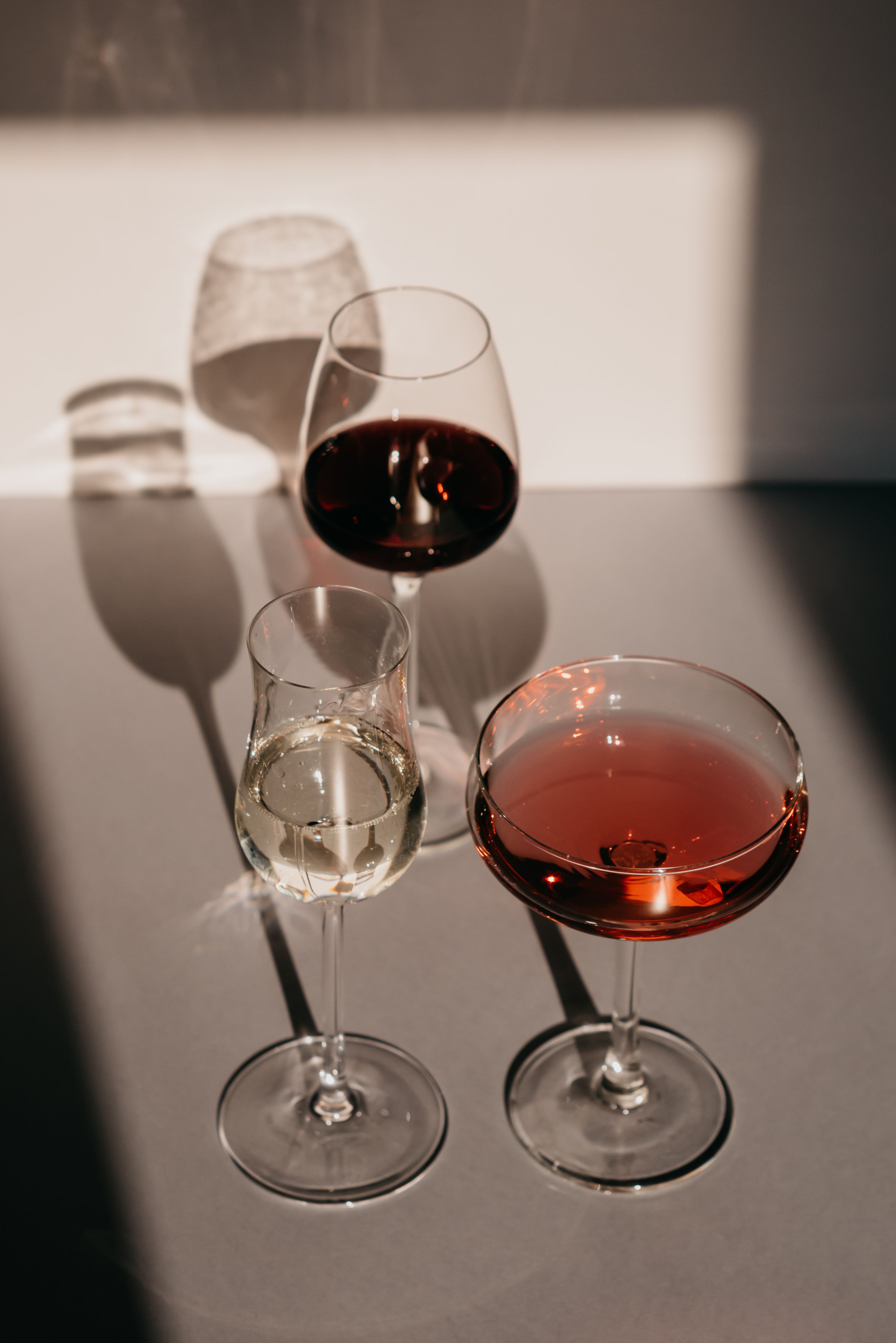 A sophisticated arrangement of wine glasses casting artistic shadows in warm sunlight