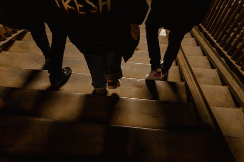 A group of people walking down a dimly lit staircase in an urban setting at night, capturing nightlife ambiance.