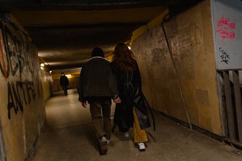 Back View of a Man and Woman Holding Hands While Walking