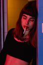 Woman in Black and Red Hoodie Smoking Cigarette