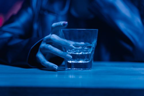 Free A dramatic close-up of a hand holding a whiskey glass with a blue tint, showcasing a nightlife vibe. Stock Photo