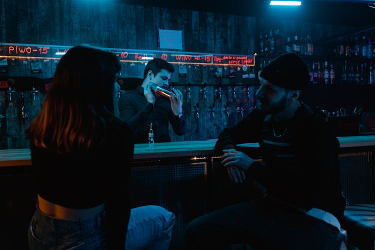 People Sitting And Talking On A Bar Counter In Front Of A Bartender