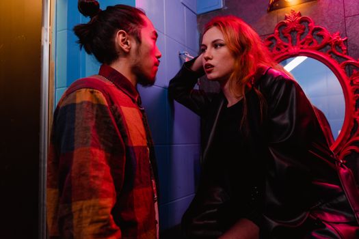 A young couple engaged in a deep conversation in a dimly lit room, surrounded by vibrant decor.