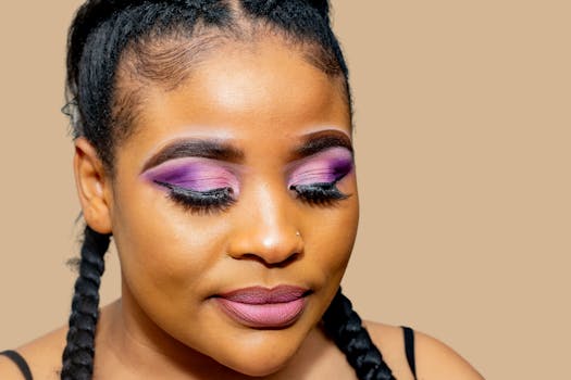 Close-up portrait of woman with purple makeup and braids, showcasing beauty and elegance.