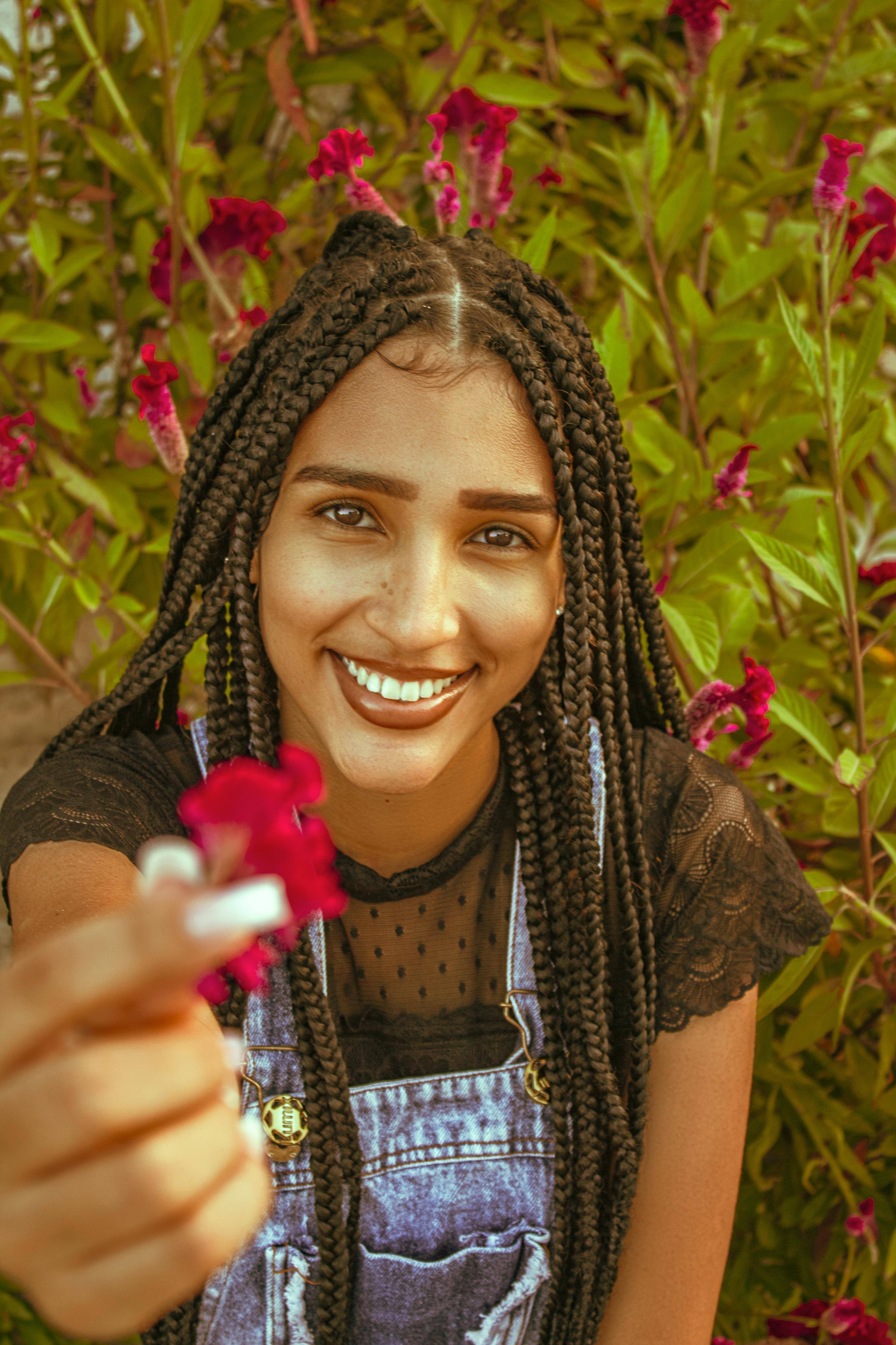 portrait of a woman with braids holding a pink flower