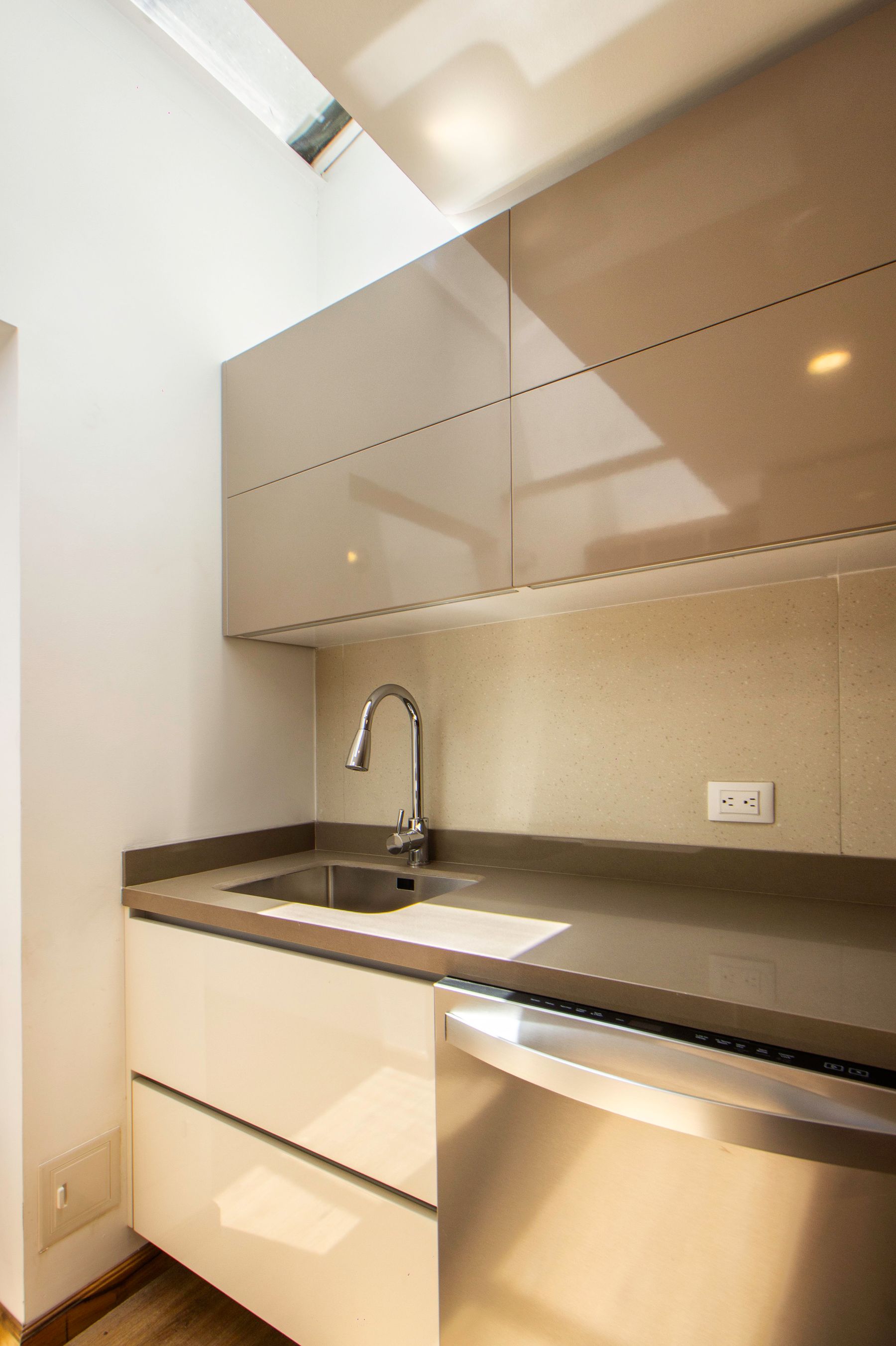 Bright streamlined kitchen counter with pale cupboards and a stainless sink