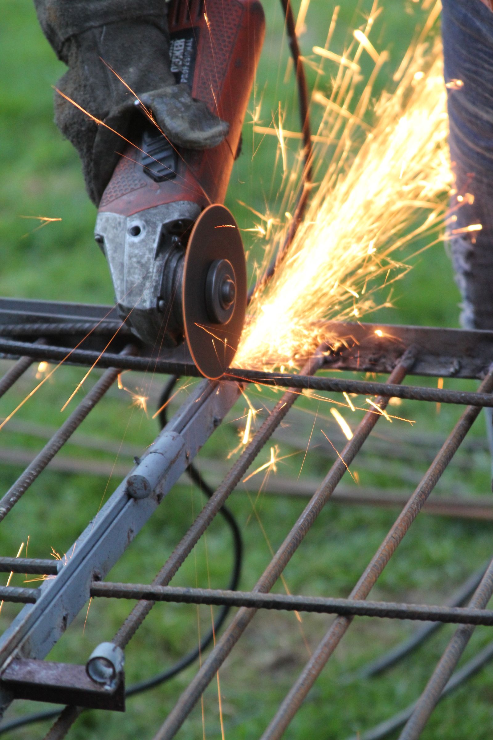 Worker wearing gloves and safety glasses using an angle grinder on metal with sparks