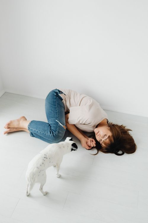 Free A woman naps on the floor with a small dog inside a bright room. Stock Photo