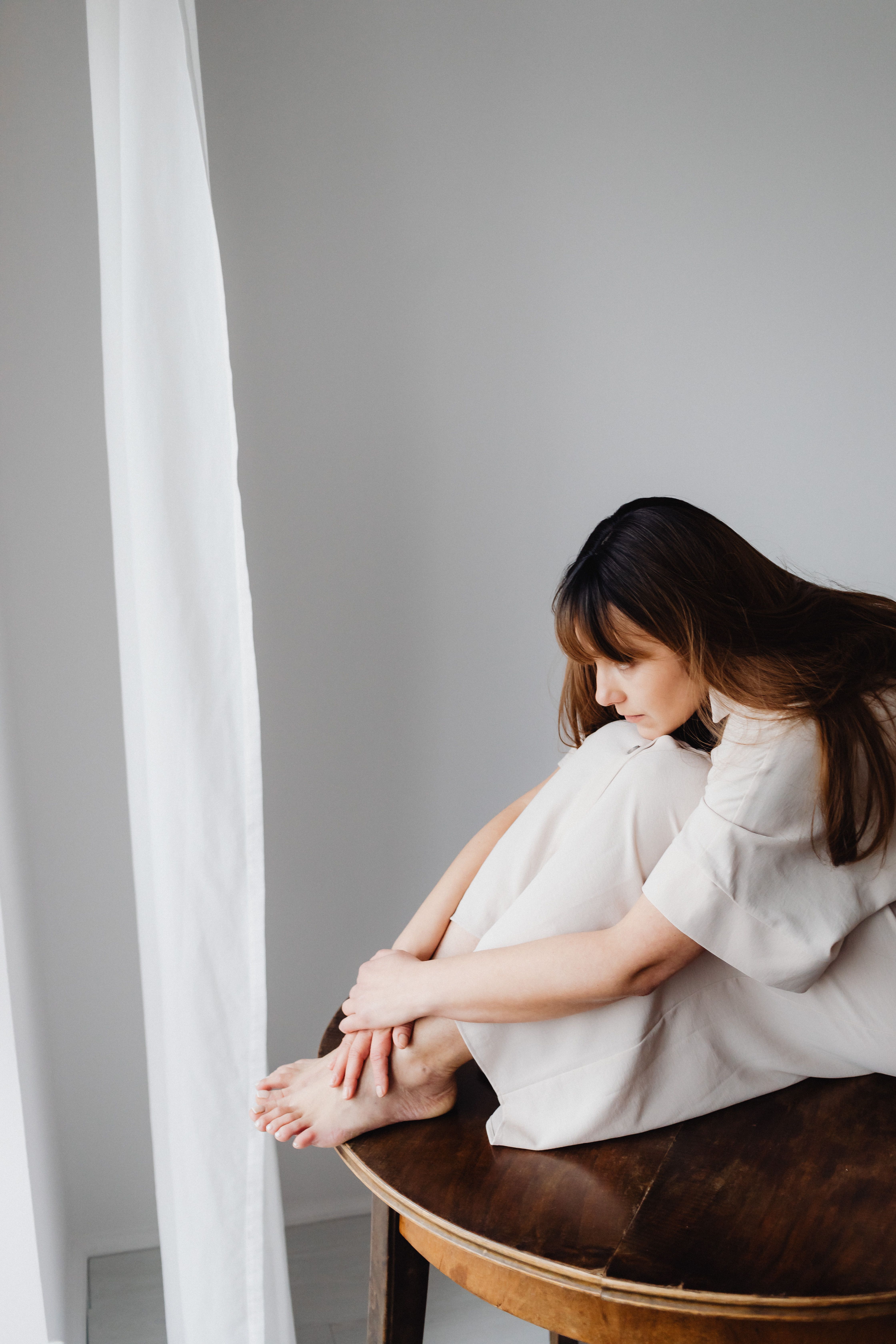 Woman in White Dress Sitting on Brown Wooden Table · Free Stock Photo