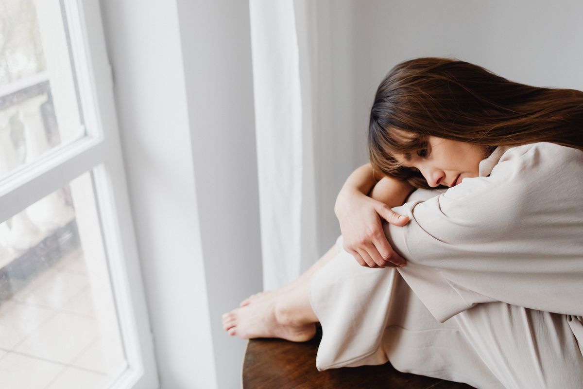 Vrouw alleen bij het raam, wachtend op een bericht
