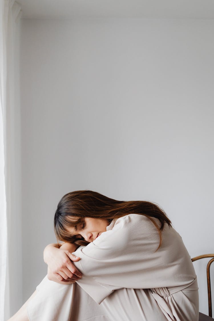 Woman Sitting In Chair Hugging Her Knees