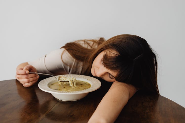 Woman Holding A Spoon And Eating A Soup