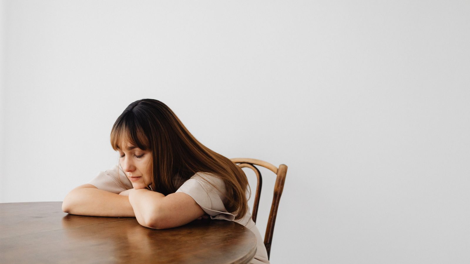 A woman resting with her eyes closed at a wooden table