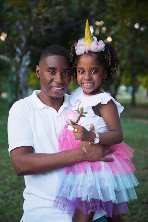 A Man in White Polo Shirt Carrying His Daughter