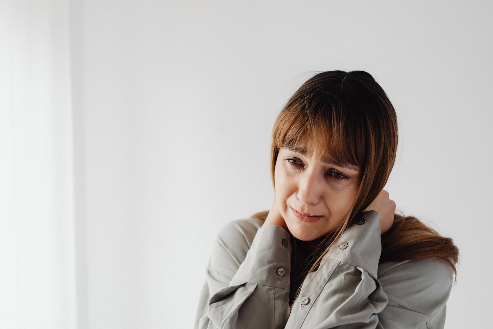 Bright home workspace scene with a person holding the side of the neck after strain