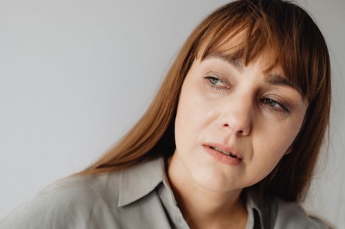 Free A thoughtful woman with bangs, wearing a gray shirt, looks away seriously. Stock Photo