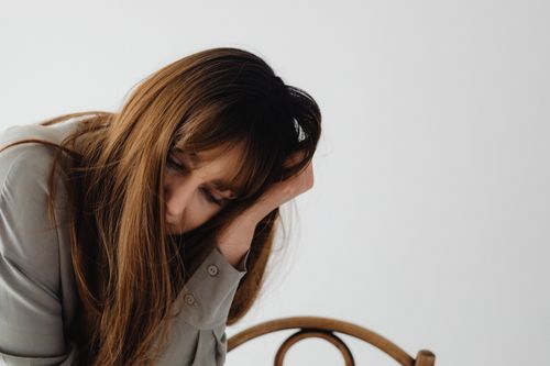 Free A contemplative woman rests her head in her hand indoors, depicting a moment of reflection and introspection. Stock Photo