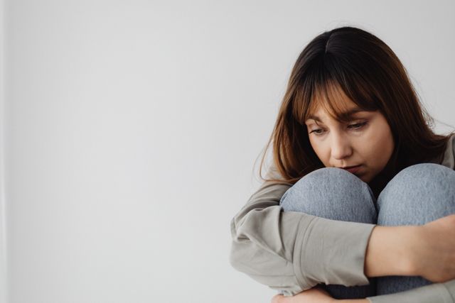 A woman sitting quietly, hugging her knees