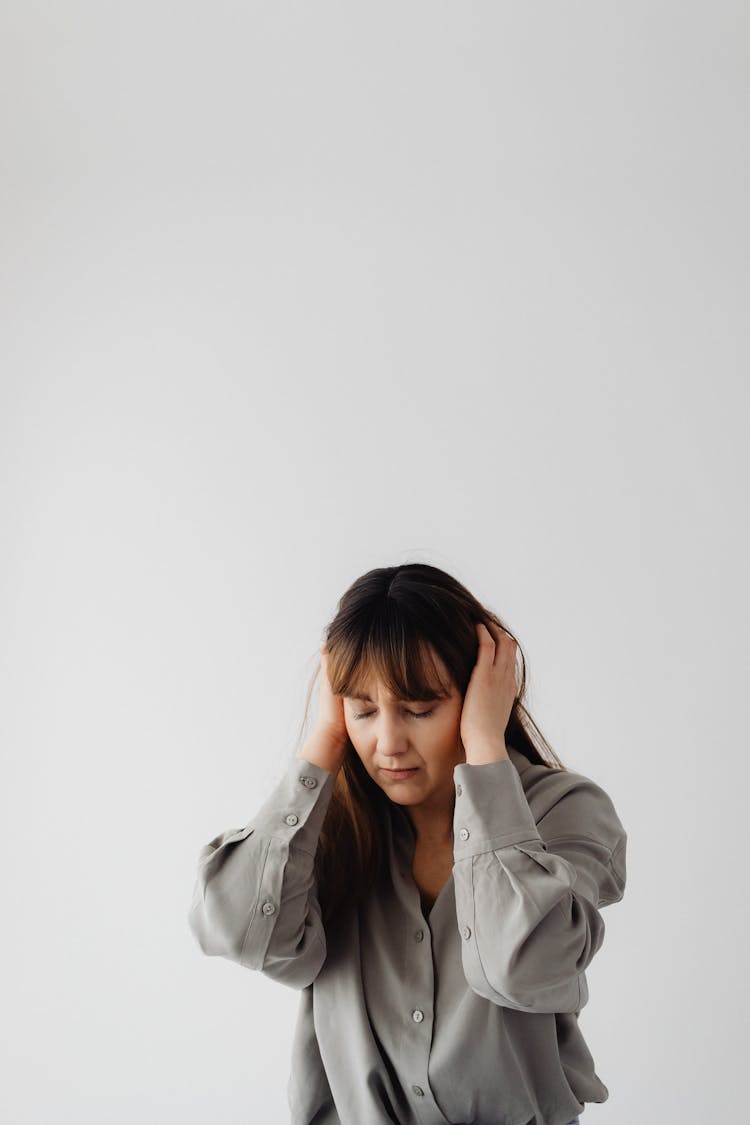 Woman In Gray Long Sleeves With Eyes Closed And Hands On Her Ears