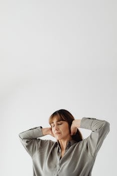 Adult woman with long hair and closed eyes posing against a minimalist gray background, conveying inner peace.