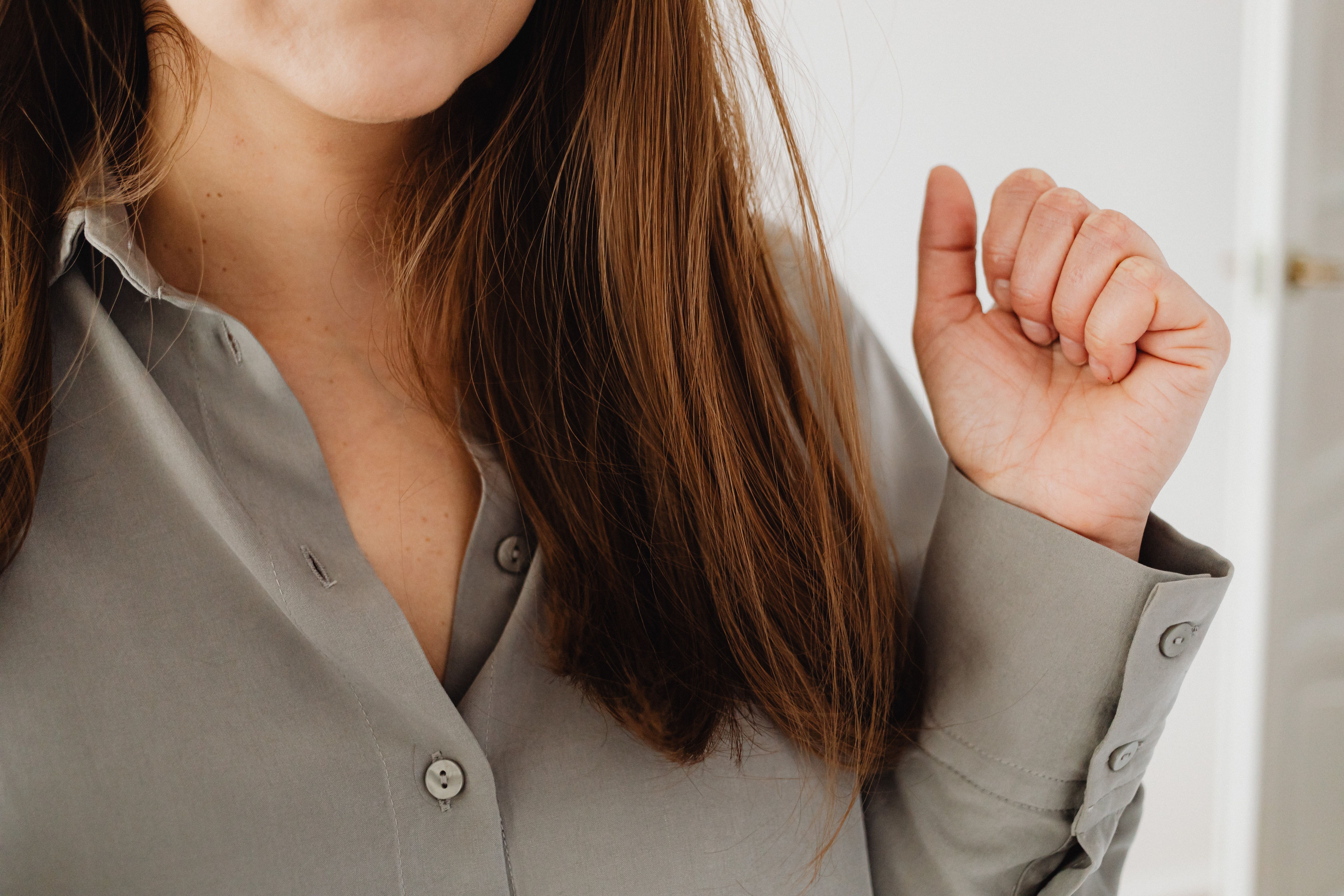 Detailed close-up of a woman with brown hair wearing a gray shirt, highlighting casual style.