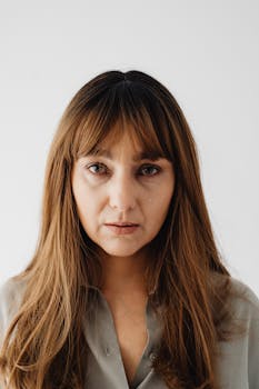 Close-up of a woman with a tear, expressing sadness on a white background.