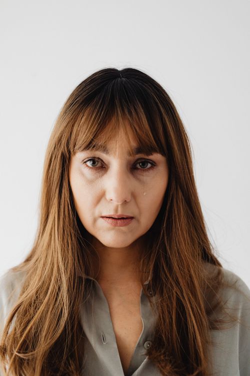 Free Close-up of a woman with a tear, expressing sadness on a white background. Stock Photo