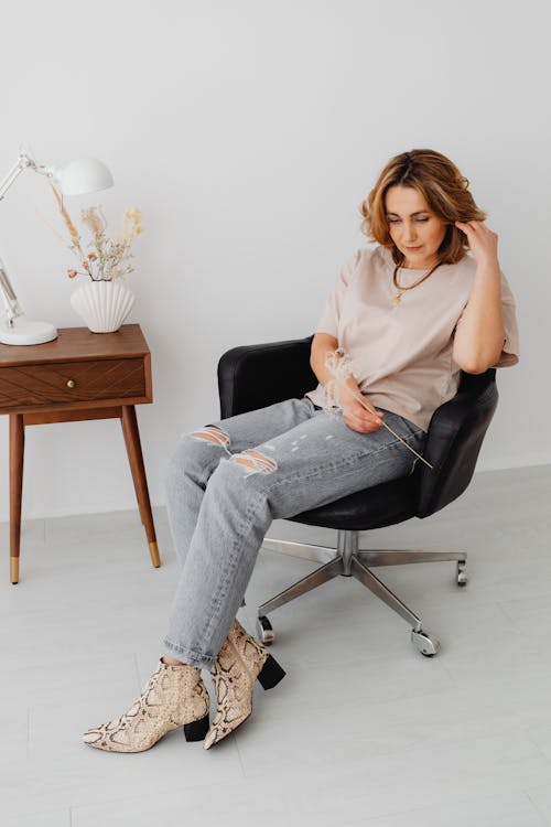 A Woman Sitting on an Armchair While Looking Serious