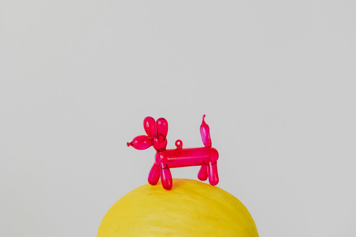 Pink balloon animal sculpture on a yellow surface
