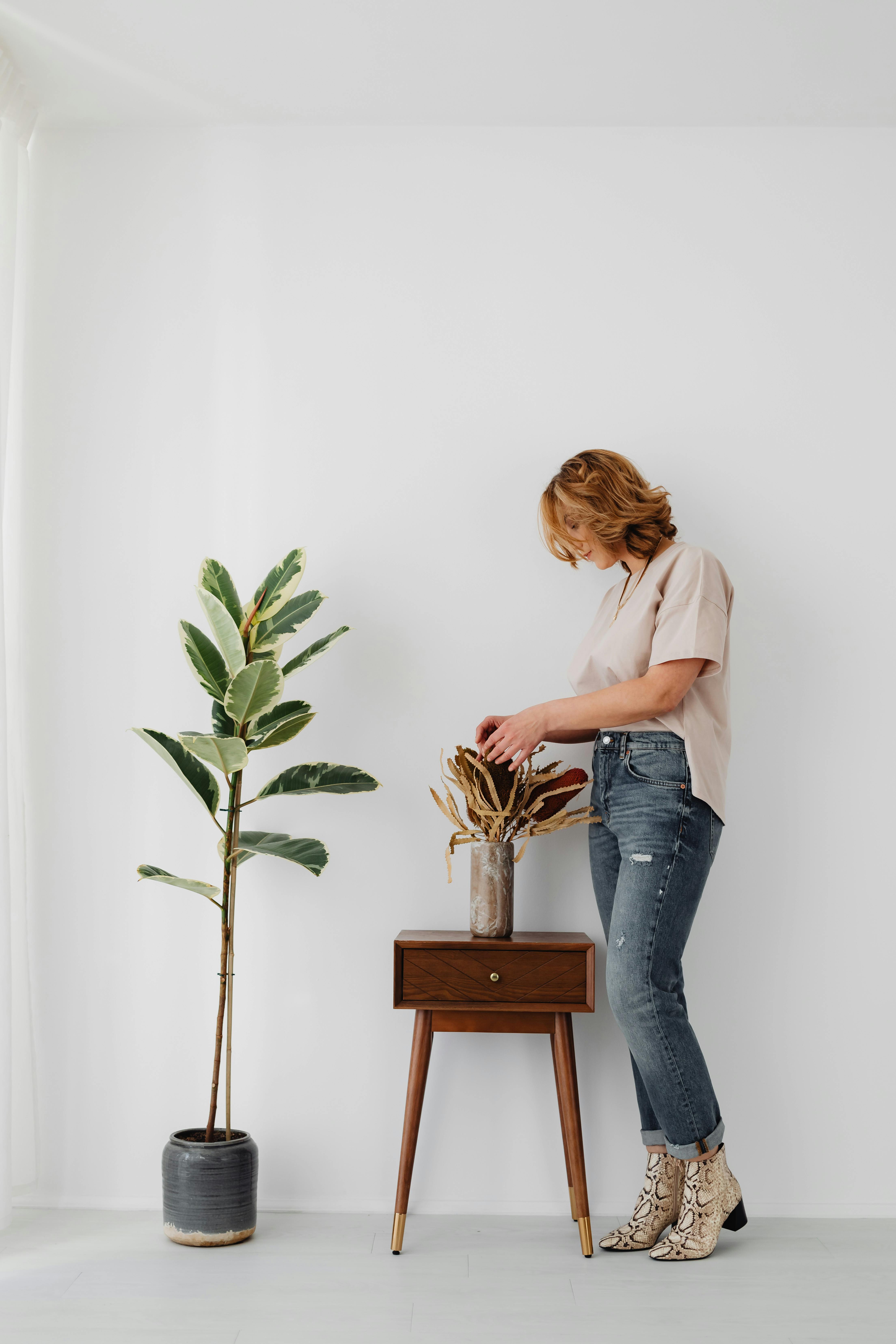 a person arranging banksia flowers in a vase