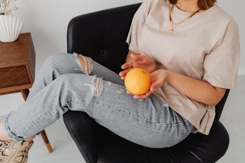 A Person Holding a Fruit while Sitting in an Armchair