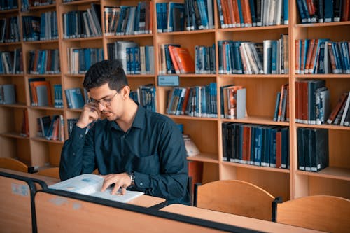Free Man Reading a Book Inside the Library Stock Photo