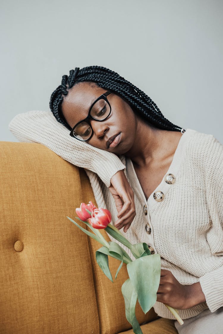 Sad African American Woman On Couch With Flowers