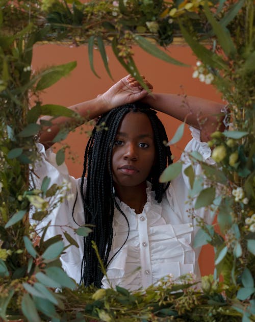 Confident black lady near frame with flowers and plants