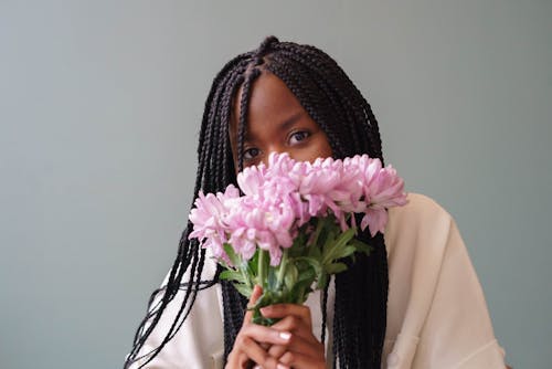 Free Black woman with blooming Chrysanthemums on gray background Stock Photo