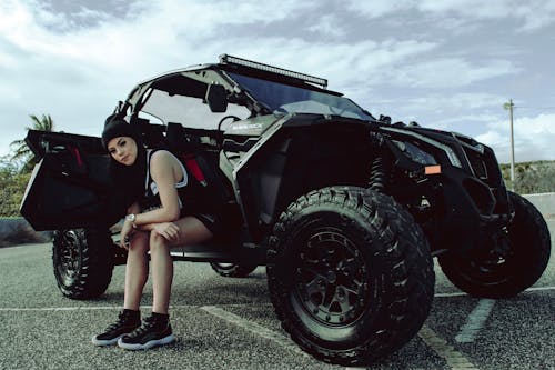 Free A stylish woman posing with a rugged off-road vehicle in an urban environment, showcasing adventure and fashion. Stock Photo