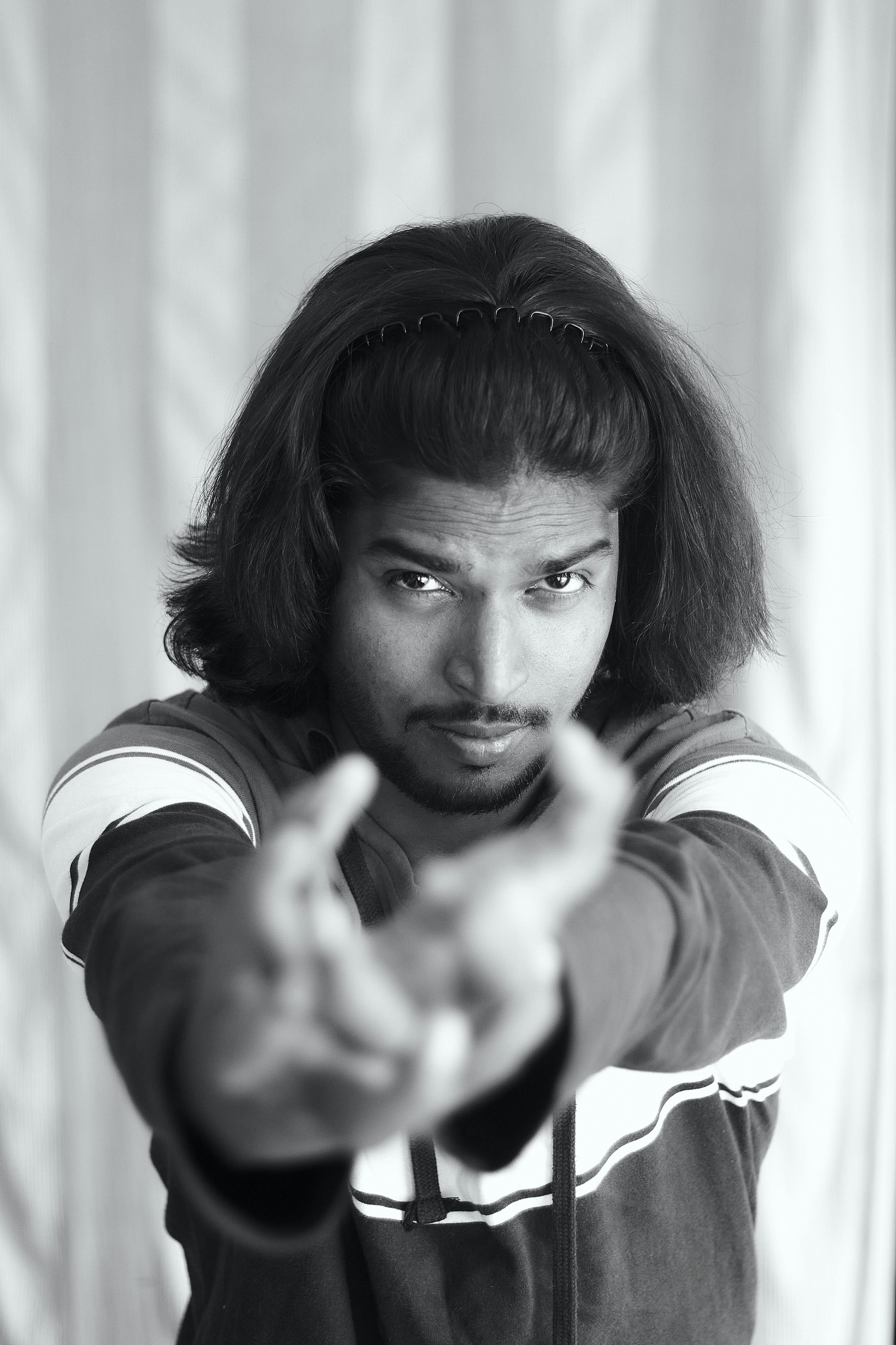Free A striking monochrome portrait of a man with long hair and a confident gaze, captured indoors. Stock Photo