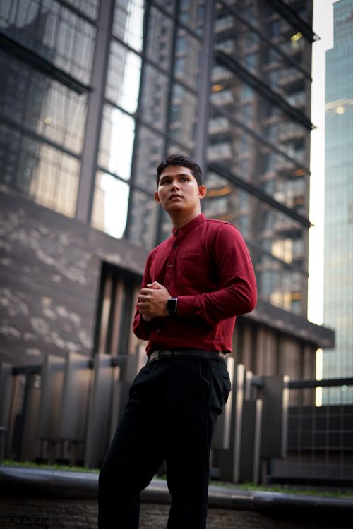 Free Handsome man in red shirt posing stylishly against a city background Stock Photo