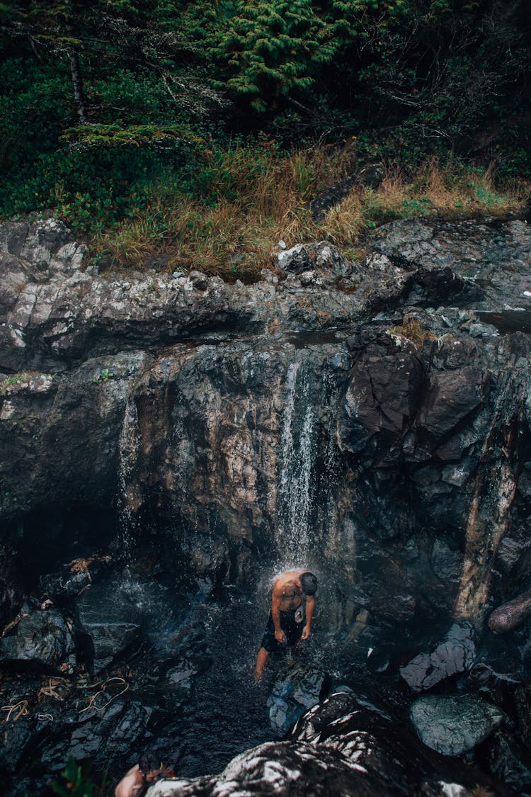 Man Showering Under A Waterfall 