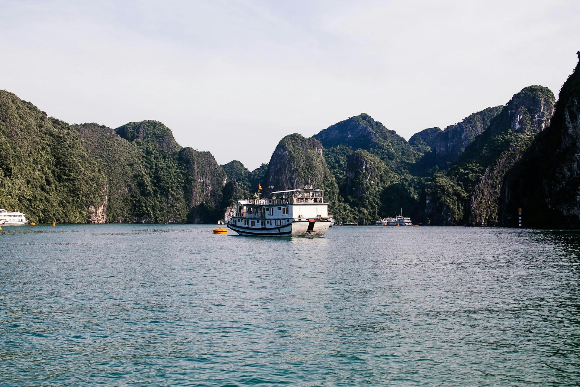 Majestic cruise boat navigating the serene waters of Halong Bay, surrounded by towering limestone islands.